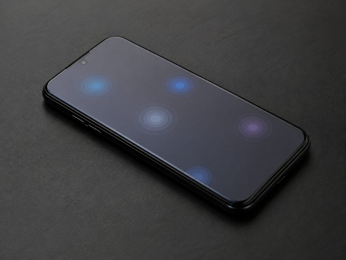 暗い机に置かれた一般的なスマートフォンの画面上に複数の淡いタッチ表示が見える様子