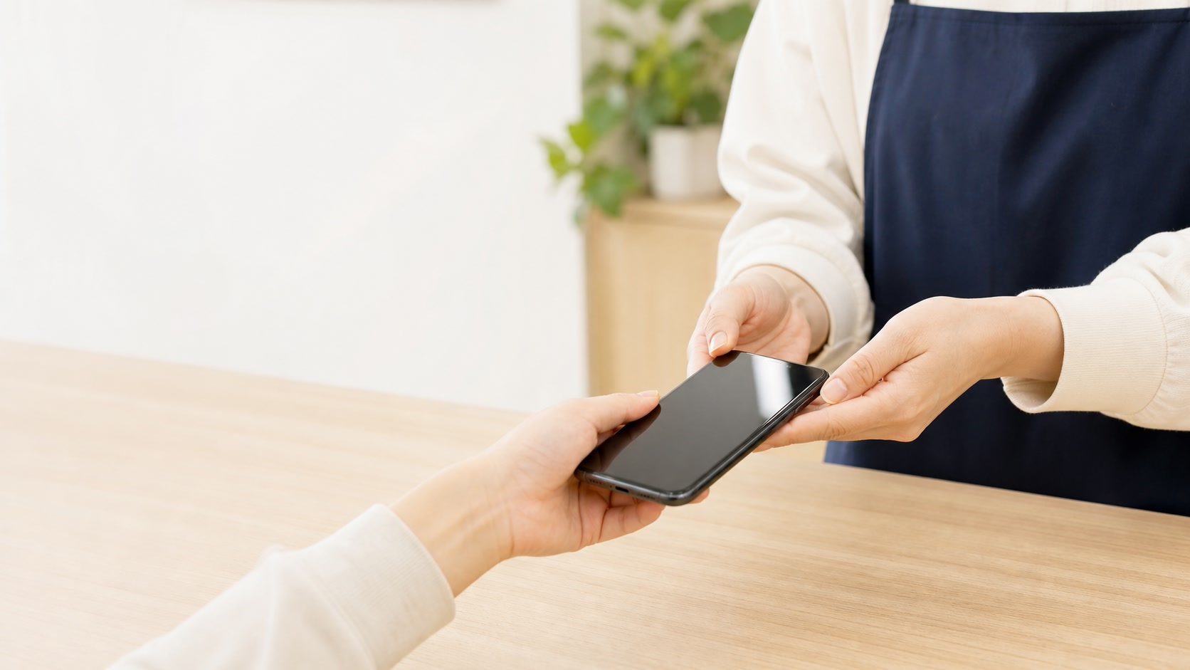スマートフォンを店舗スタッフへ渡して査定を依頼する様子