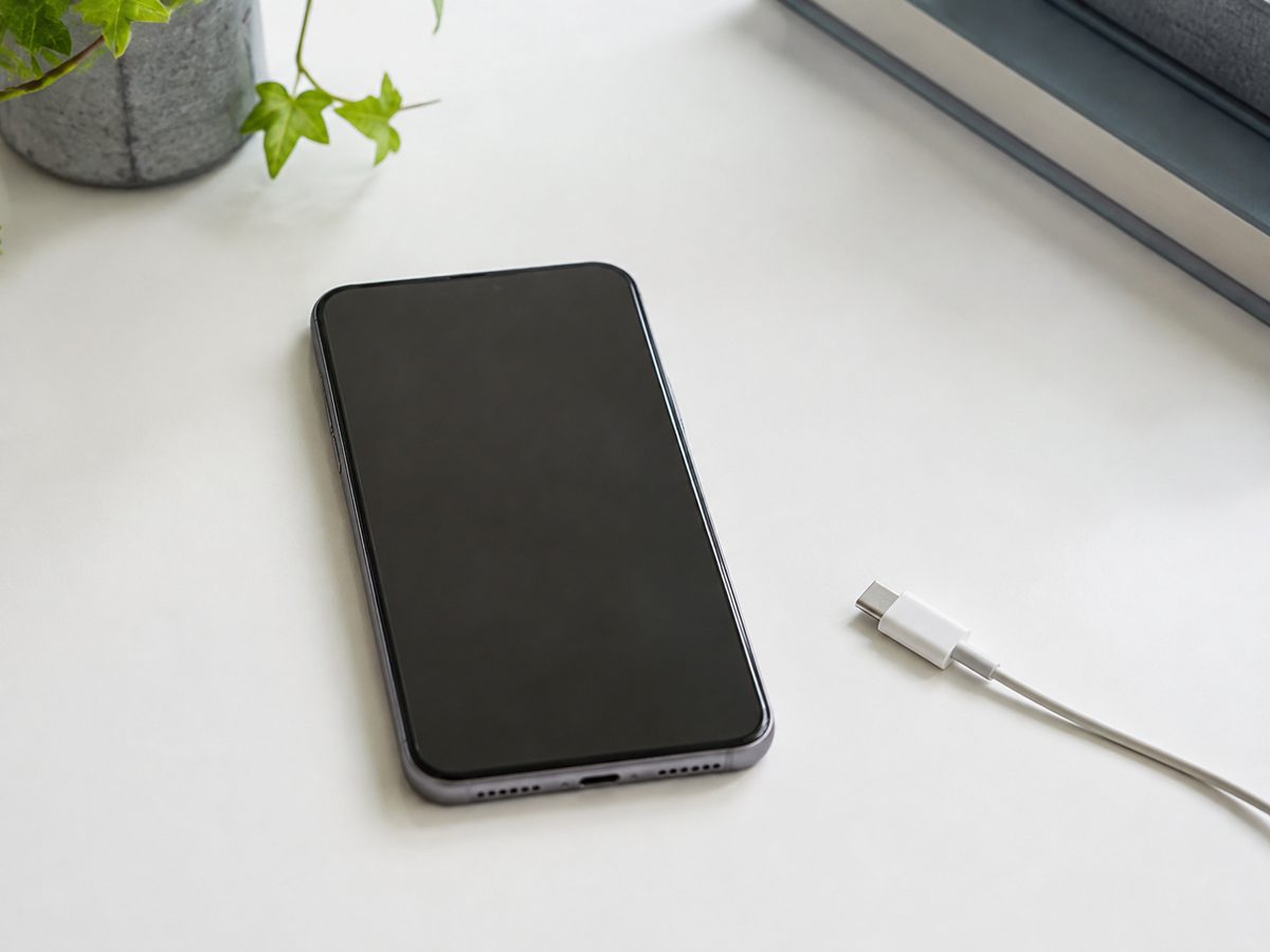 ケーブルを離して机に置かれた無表示のスマートフォン